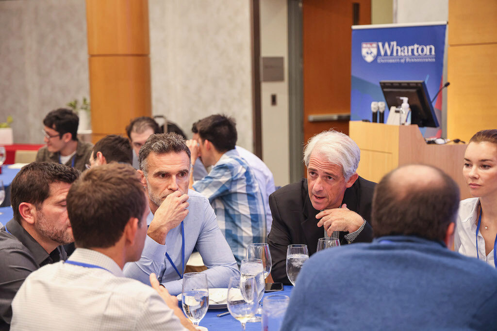 Itay Goldstein sits at a table with conference attendees