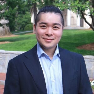 A headshot of a person before an outdoor setting
