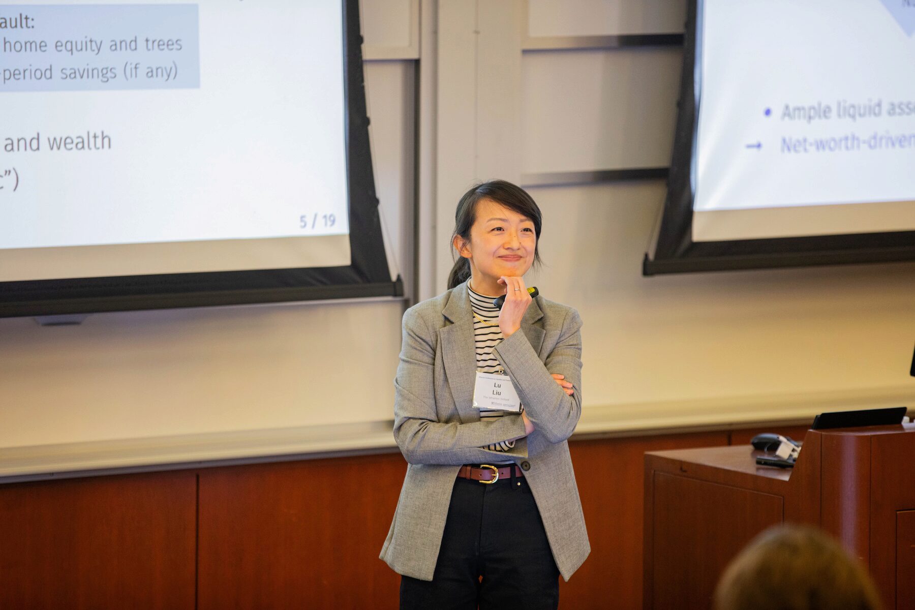 A conference speaker smiles toward the audience